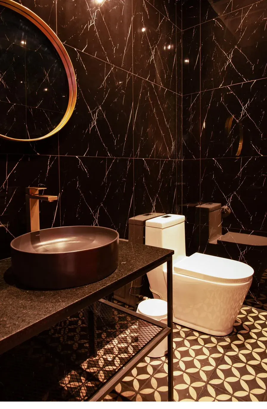 Baño dorado · espejo circular y mármol negro