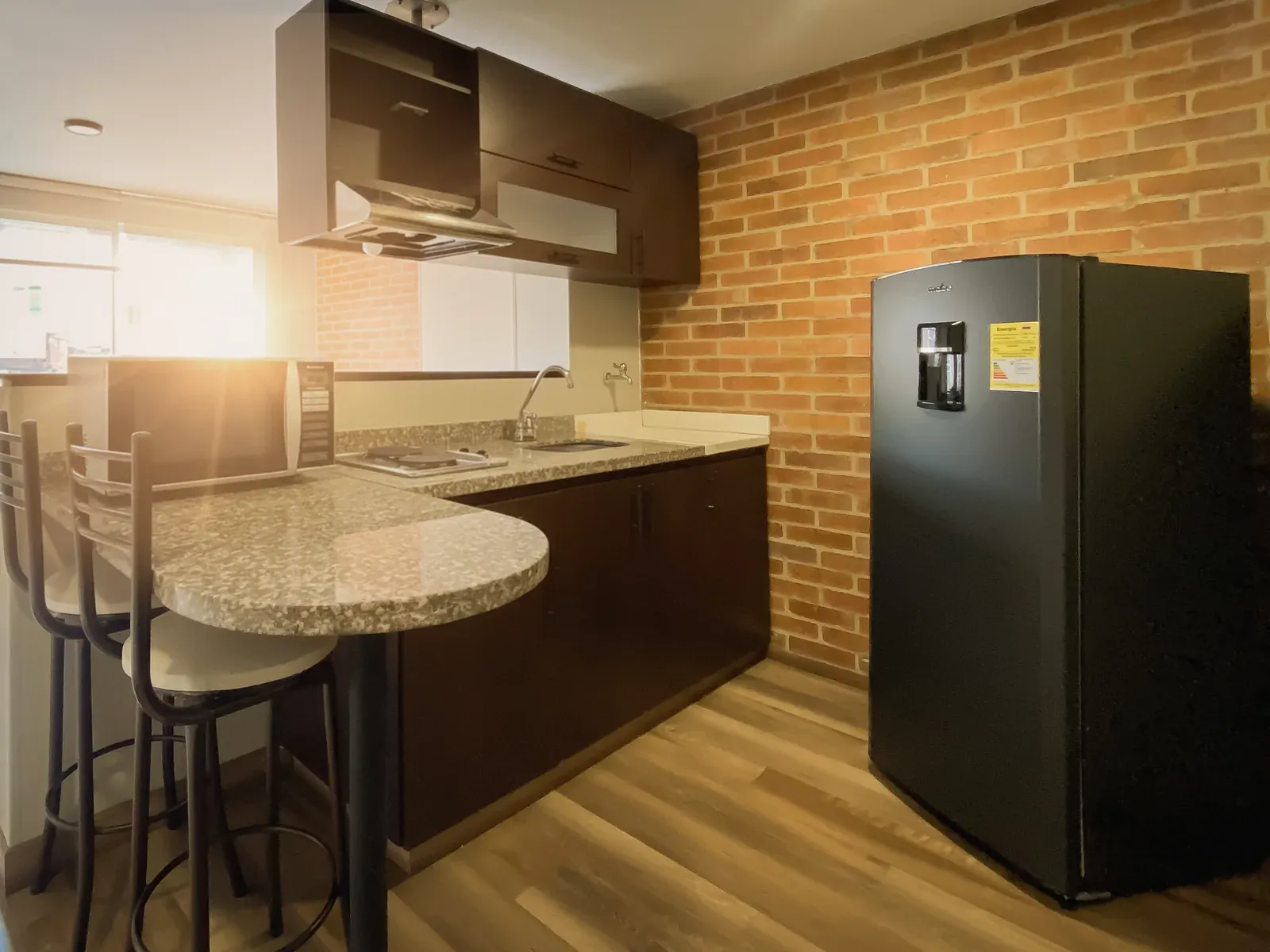 Cocina completa con nevera y muro en ladrillo